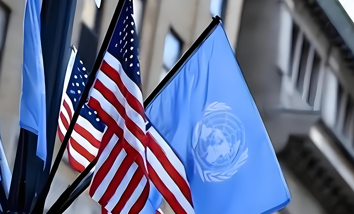 "American flag and United Nations flag waving side by side in front of a government building, symbolizing international cooperation."